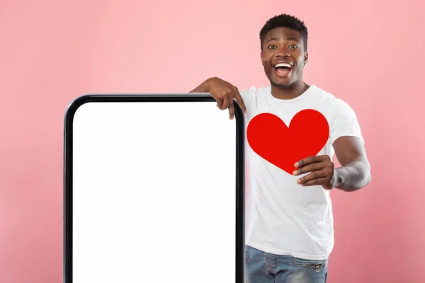 흰색빈 스마트폰 화면에 종이 심장을 들고 있는 흑인 남자 — 스톡 사진