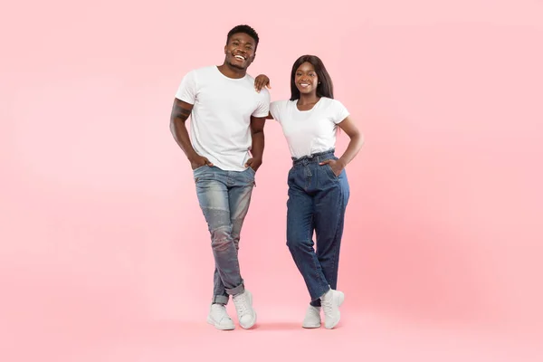 Confident couple standing posing at pink studio background —  Fotos de Stock