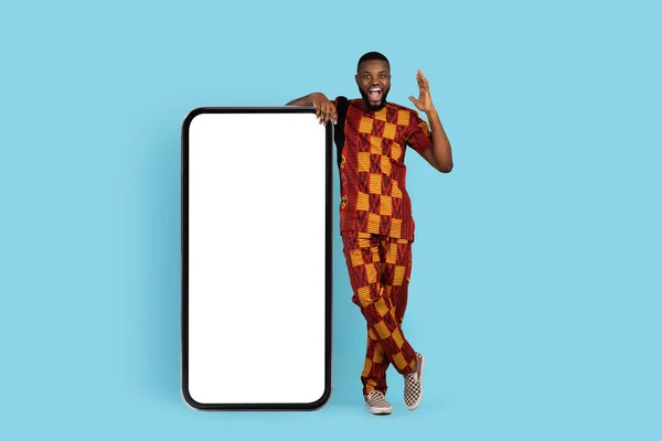 Excited Black Man In Traditional Clothing Standing Near Big Blank Smartphone — 图库照片