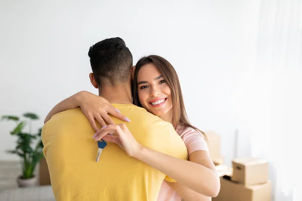 Concepto de hipoteca y reubicación. Feliz dama caucásica abrazando a su novio, sosteniendo la llave de la nueva casa —  Fotos de Stock