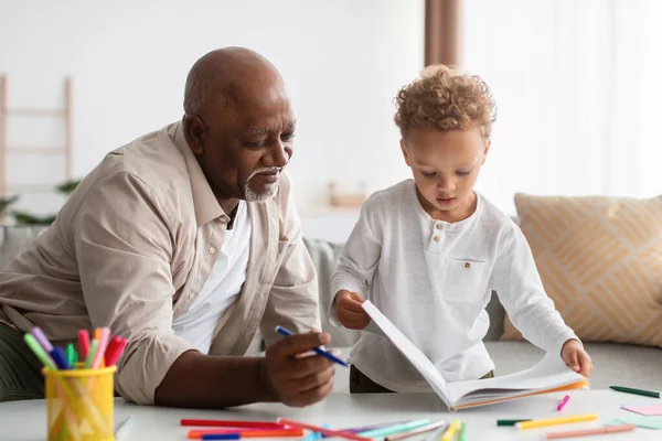 African American Little Boy Showing Drawings To Grandpa At Home — Stock Fotó
