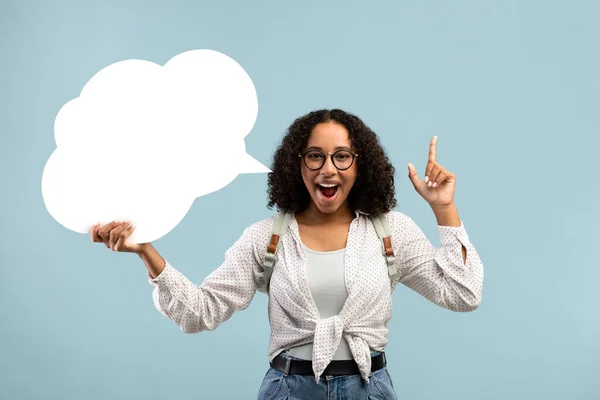 Happy black woman holding blank speech bubble, having creative idea on blue studio background, mockup for design — Zdjęcie stockowe