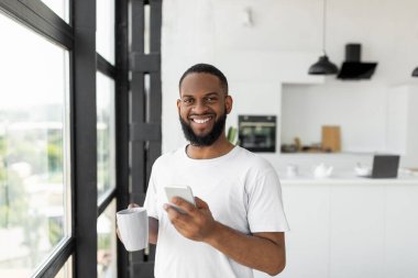 Black man using his smartphone drinking coffee