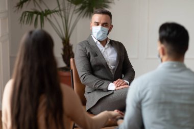 Terapi seansında maske takmış genç bir çift.