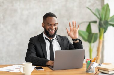 Black man having video call using pc and waving