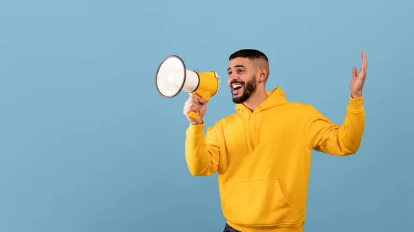 Promo announcement. Happy arab guy with megaphone in hands sharing news or interesting offer, blue background — Stock fotografie