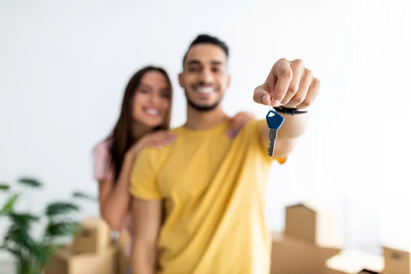 Cheerful young international couple showing house key, feeling happy about moving to new home, selective focus — Stockfoto