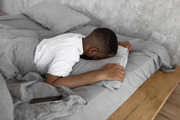 Giovane uomo afroamericano che dorme a letto con il cellulare — Foto Stock