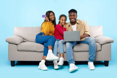 Happy black family using laptop computer and credit card
