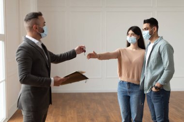 Real Estate Agent In Facemask Giving Keys To Excited Buyers