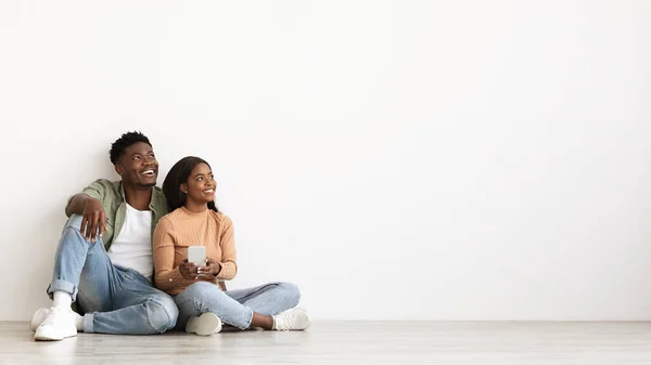 Cheerful black couple with smartphone looking at copy space — Foto Stock