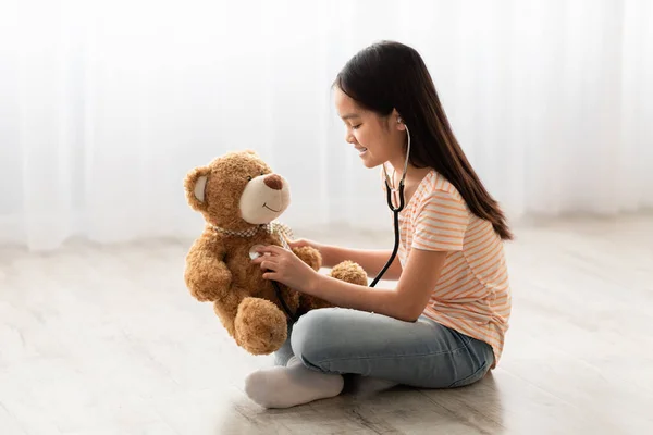 Cute little asian girl playing doctor with teddy bear — Photo