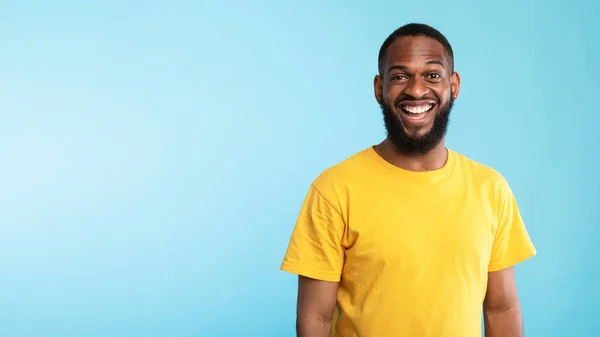 Positive young black man in casual wear smiling and looking at camera on blue background, panorama with empty space — 스톡 사진