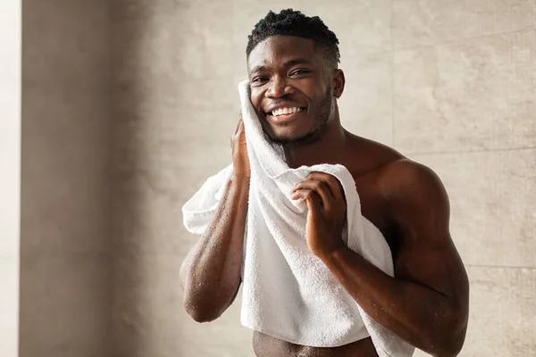 Afro-américain mâle essuyant visage après lavage debout dans la salle de bain — Photo