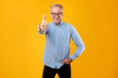 Mutlu olgun adam başparmak işareti yapıyor ve gülümsüyor.