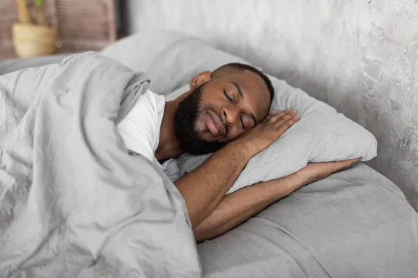 Young African American man lying in bed and sleeping — Fotografia de Stock