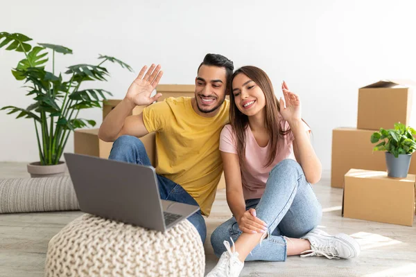 Loving multiracial family using laptop at their new home, sitting on floor, having online video call with friends or family — Foto Stock