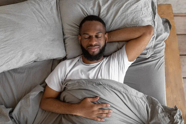 Νεαρός Αφροαμερικάνος ξαπλωμένος στο κρεβάτι και κοιμάται — Φωτογραφία Αρχείου