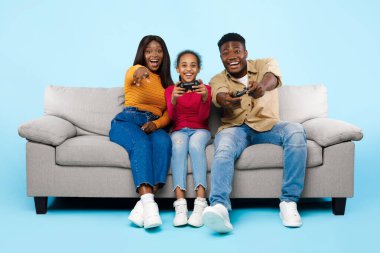 Excited African American family playing video games together with joysticks