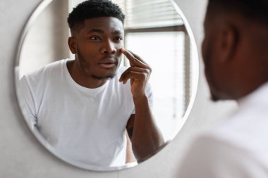 Black Man Touching Face Caring For Under-Eye Skin In Bathroom