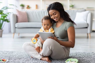 Happy Black Mother And Toddler Child Relaxing With Digital Tablet At Home