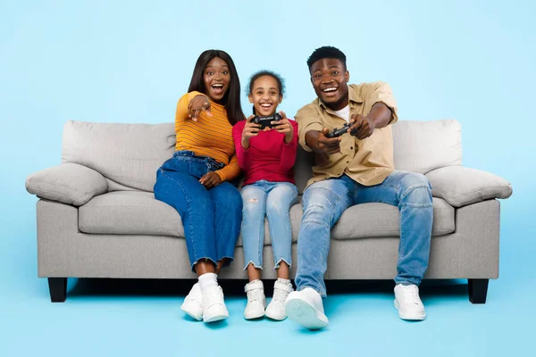Excited African American family playing video games together with joysticks — Stockfoto