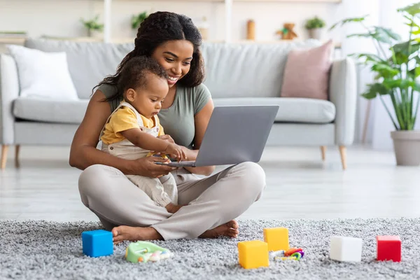 Niños y tecnología. negro mamá y poco bebé usando portátil en casa — Foto de Stock