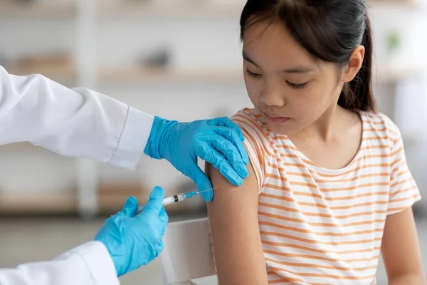 Unrecognizable doctor making vaccination for asian girl — Stockfoto