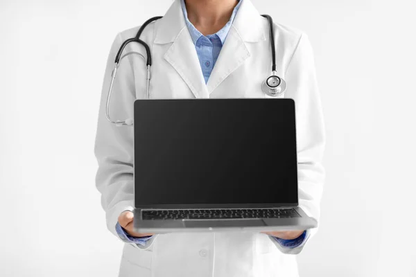 Young indian female doctor in uniform shows computer with empty screen isolated on white background, unrecognizable — Zdjęcie stockowe