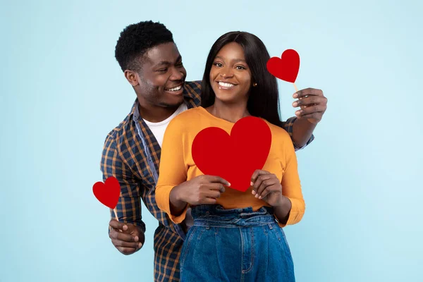 Young Romantic Black Couple Posing And Holding Red Paper Hearts — Stockfoto