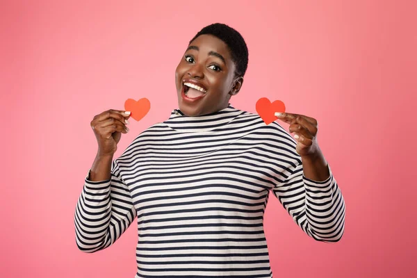 Happy African Female Showing Two Red Paper Hearts, Pink Background — Stok fotoğraf