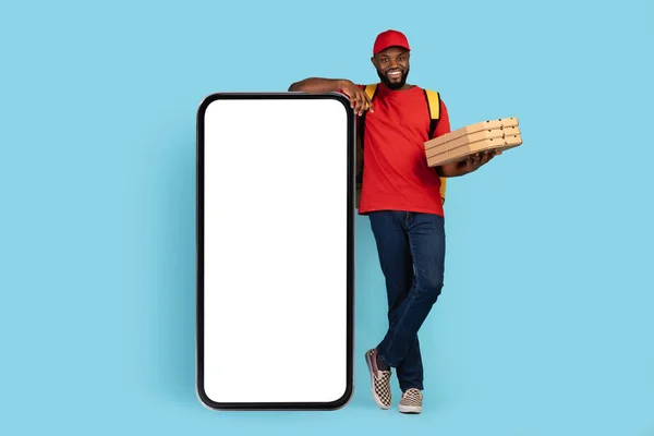 Delivery App. Black Courier Man With Pizza Boxes Standing Near Blank Smartphone — 图库照片