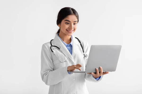 Cheerful young attractive hindu woman medical worker in uniform works at computer — Stock Photo, Image