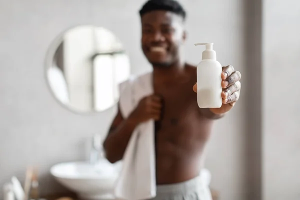 Irreconocible afroamericano hombre mostrando líquido jabón botella en cuarto de baño — Foto de Stock