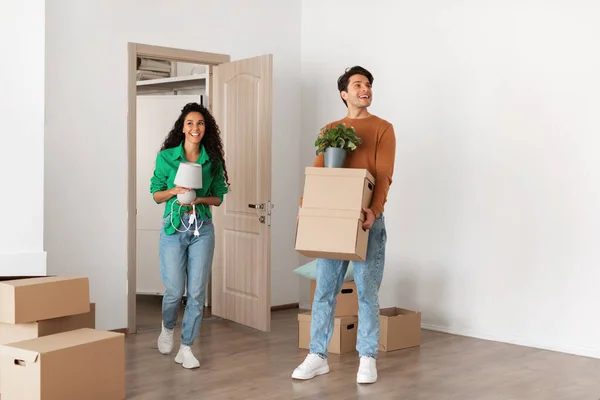 Pareja feliz sosteniendo cajas de cartón, caminando en casa nueva — Foto de Stock