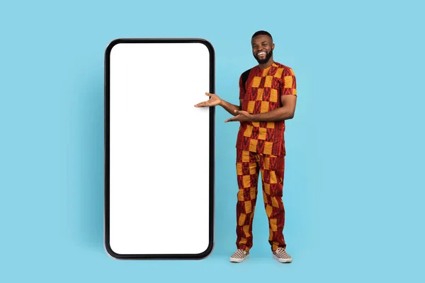 Great App. African Man In Traditional Costume Pointing At Big Blank Phone — Stock fotografie