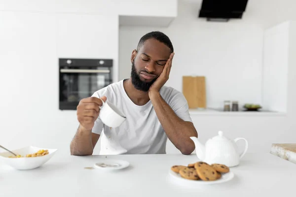 Black man yawning, pouring coffee away from cup — Stock Photo, Image