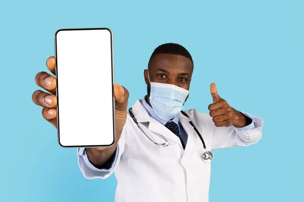 Black Doctor In Medical Face Mask Demonstrating Blank Smartphone Screen At Camera — Stock fotografie