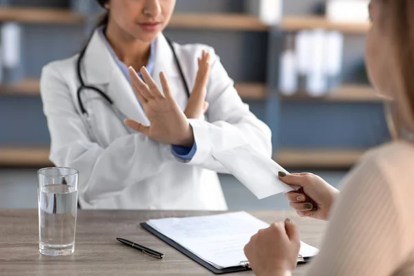 Serious young hindu female therapist in uniform, makes sign, crossed arms and says no to patient with money — Fotografia de Stock