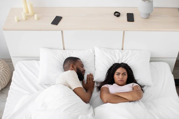 Upset young black woman lie on white bed with crossed arms on her chest think about problems, suffers from noise — Foto Stock