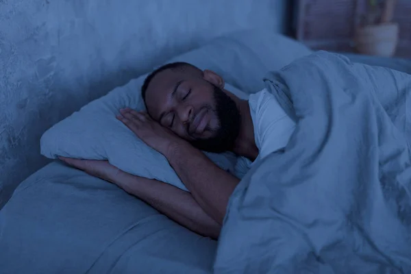 Joven hombre afroamericano acostado en la cama y durmiendo — Foto de Stock