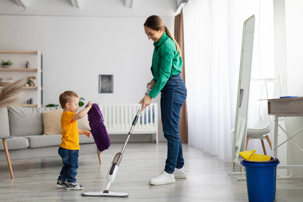 Lets tidy up together. Mother and kid son do the cleaning in the house, little boy helping mom, woman mopping floor