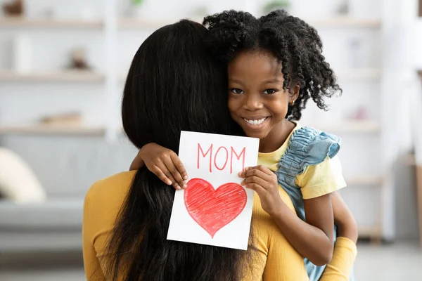 可爱的黑人小女孩拿着手工制作的贺卡拥抱妈妈 — 图库照片
