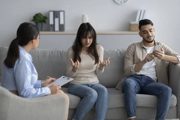 Irritated arab woman blaming husband at psychologist consultation, complaining about his smartphone addiction — Stock Photo, Image