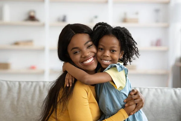 快乐的年轻黑人母亲和她可爱的未成年女儿在家里拥抱 — 图库照片