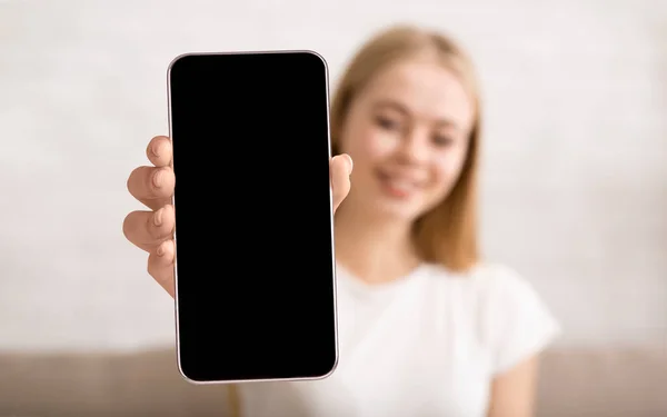 Young woman showing smartphone with big blank screen at camera, lady demonstrating space for mobile app or website — Stok Foto