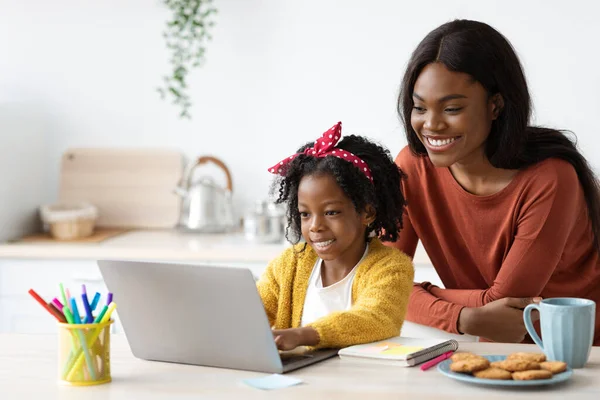 Caring Black Mom Helping Little Daughter With Online Education, Making Homework Together
