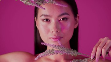 Korean Cosmetics Concept. Beautiful Asian Female Holding Flowers And Looking At Camera