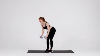 Young Sporty Female Doing Dumbbell Bent Over Fly Exercise In Studio
