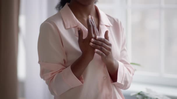 Невпізнавана чорна жінка застосовує крем зволожувач на руці вдома — стокове відео